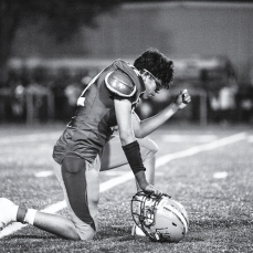 A New Deal player drops to one knee in prayer prior to the start of a game at Noland Stadium in New Deal, Texas.
